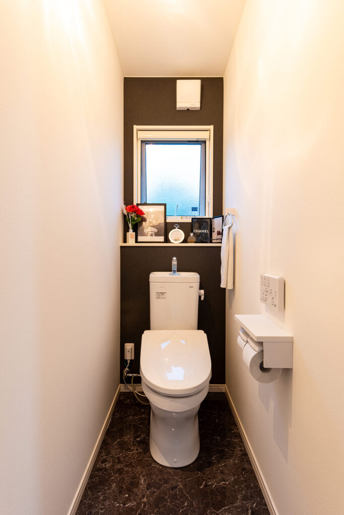トイレは黒いクロスと大理石調のフロアタイルがアクセント。窓の手前には小物を飾れるライニングが。